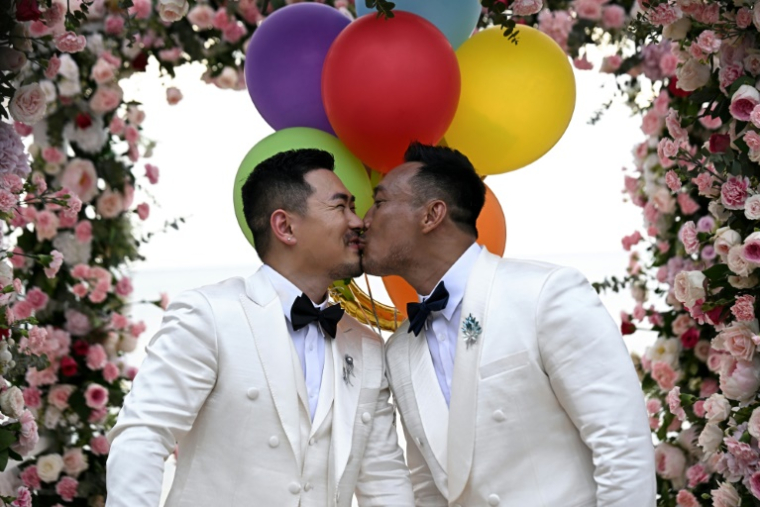 Les Chinois Song Jihan (g) et Wang Zengyi s'embrassent lors de la cérémonie de leur mariage près de Pattaya, dans la province de Chonburi, le 31 mai 2025 en Thaïlande ( AFP / Lillian SUWANRUMPHA )