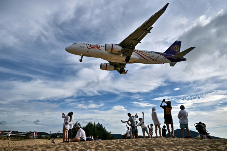 Des touristes sur la plage de Mai Khao, sur l'île de Phuket, près de l'aéroport international, le 18 novembre 2023 en Thaïlande ( AFP / Lillian SUWANRUMPHA )