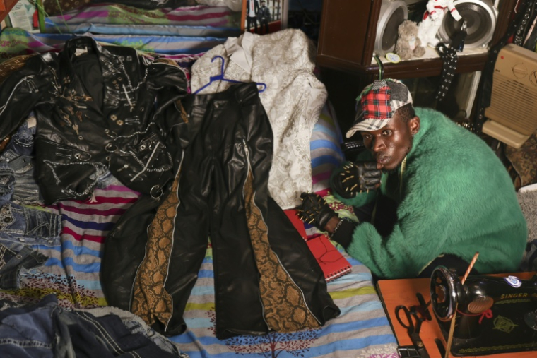 Le créateur de mode Morgan Azedy et quelques-unes de ses créations fabriquées à partir de tissus récupérés sur des marchés de vêtements d'occasion et des décharges, dans son atelier de Nairobi, le 6 octobre 2025 au Kenya ( AFP / Tony KARUMBA )