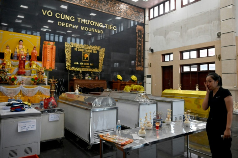 Une femme pleure devant des cercueils de victimes du naufrage d'un bateau de tourisme qui a fait au moins 35 morts dans la province vietnamienne côtière de Quang Ninh, le long de la Baie d'Halong, le 20 juillet 2025 ( AFP / Nhac NGUYEN )