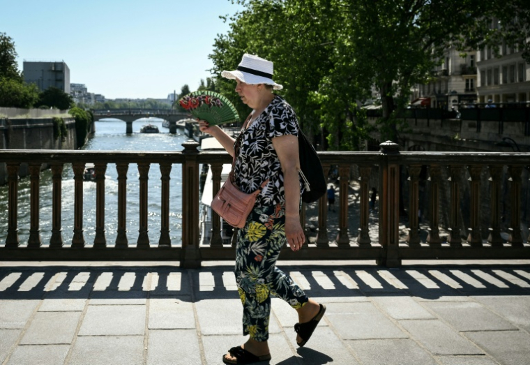 Une femme porte un chapeau et tient un éventail pour se rafraîchir à Paris, lors d'un épisode de canicule en France, le 21 juin 2026 ( AFP / ARNAUD FINISTRE )