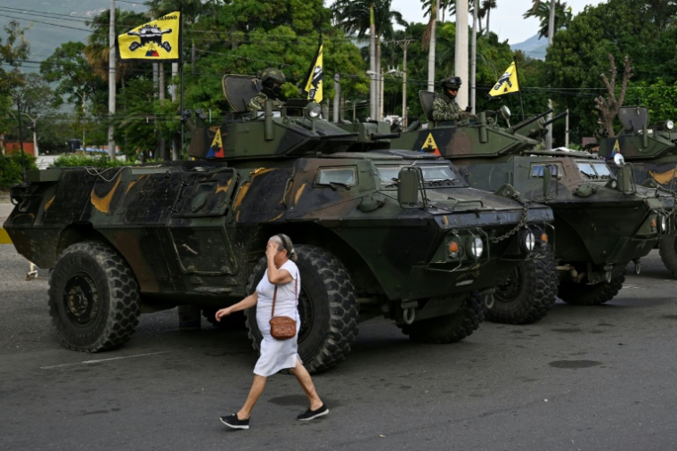 Une femme passe devant des véhicules militaires colombiens stationnés à Cucuta, à la frontière avec le Venezuela, le 3 janvier 2026 Des soldats colombiens en faction au point de passsage de Cucuta, à la frontière avec le Venezuela, le 3 janvier 2026  ( AFP / Raul ARBOLEDA )