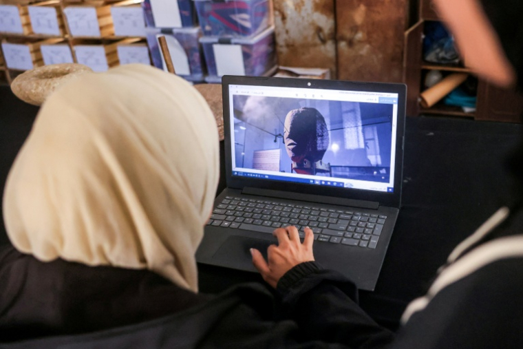 Une membre de l'association Mayasem pour la culture et les arts examine des images sur un ordinateur portable,au centre de stockage du patrimoine culturel à Khan Younès, le 11 juillet 2026 dans le sud de la bande de Gaza ( AFP / Bashar Taleb )