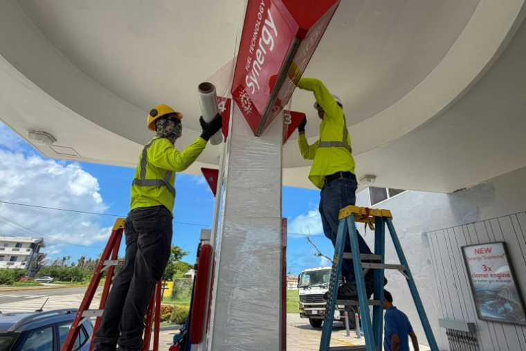 Des ouvriers consolident les panneaux d'une station service avant l'arrivée d'un "super typhon", le 4 juillet 2026 à Saipan, dans les Iles Mariannes du Nord   ( AFP / Mark RABAGO )