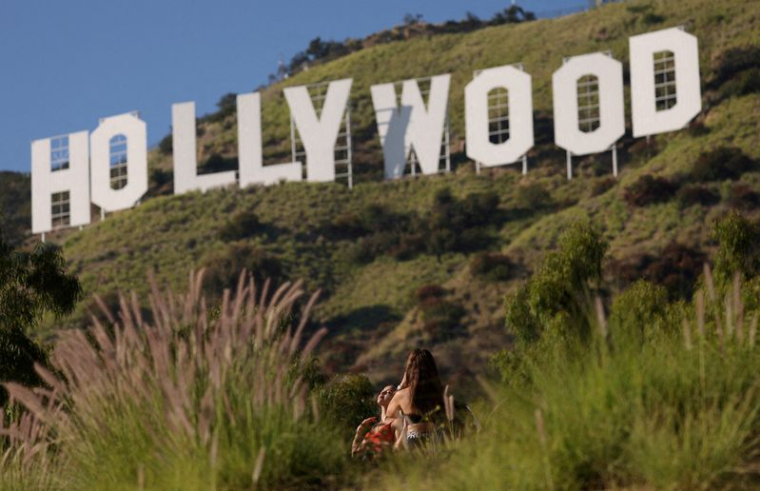 Une femme pose devant le panneau d'Hollywood, à Los Angeles