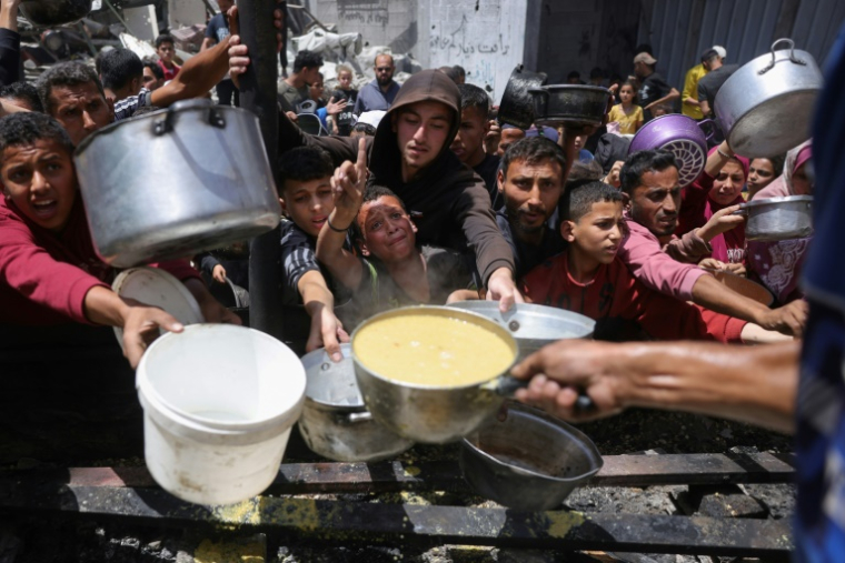 Des déplacés palestiniens se bousculent pour collecter des portions de nourriture préparées par une association caritative à Jabalia, dans le nord de la bande de Gaza, le 19 mai 2025 ( AFP / Bashar TALEB )