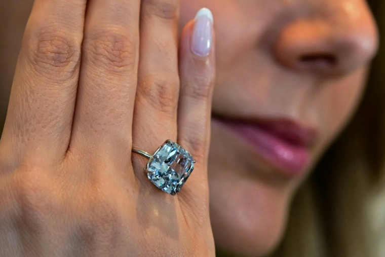 Le "Bleu Méditerranée", diamant de 10,03 carats, présenté le 8 avril 2025 à Abou Dhabi au doigt d'une employée de Sotheby's, avant sa vente aux enchères mi-mai à Genève en Suisse ( AFP / Giuseppe CACACE )