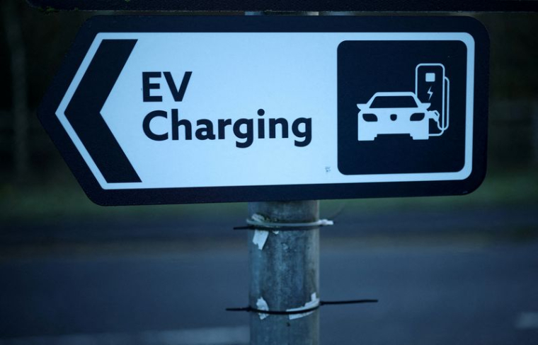 PHOTO D'ARCHIVES : Un panneau de signalisation pour les voitures est accroché à un lampadaire près d'une station de recharge pour véhicules électriques à Manchester.