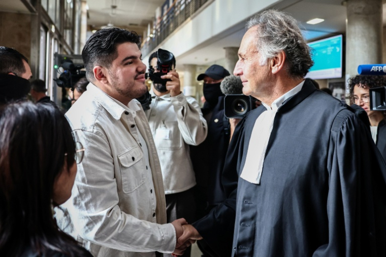 Amine Kessaci serre la main de son avocat, Me Pierre-Olivier Sur, au palais de justice d'Aix-en-Provence le 19 octobre 2026 ( AFP / Thibaud MORITZ )