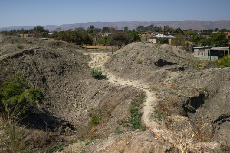 Un chemin passe entre des tas de terre extraits par des mineurs illégaux à la recherche de chrome à Bapong, un village minier de la province du Nord-Ouest (Afrique du Sud), le 25 août 2026 ( AFP / EMMANUEL CROSET )