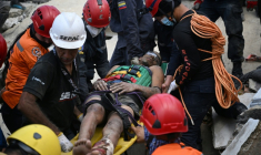 Des membres de la protection civile vénézuélienne et des pompiers sortent un jeune homme des décombres d'un immeuble effondré à Catia La Mar, dans l'Etat de La Guaira, au Venezuela, le 26 juin 2026 ( AFP / Federico PARRA )