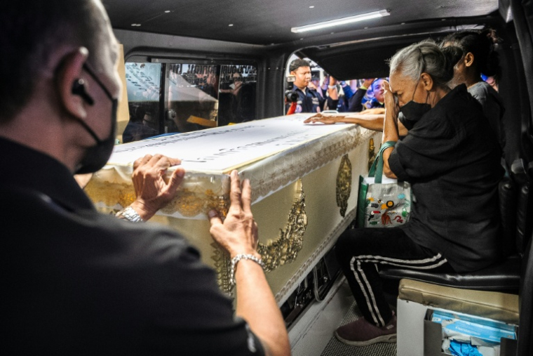 Une proche endeuillée accompagne le cercueil contenant la dépouille d'une victime de l'incendie d'un bar, dans un fourgon funéraire, le 14 juillet 2026 à l'hôpital général de la police de Bangkok, en Thaïlande ( AFP / chanakarn LAOSARAKHAM )