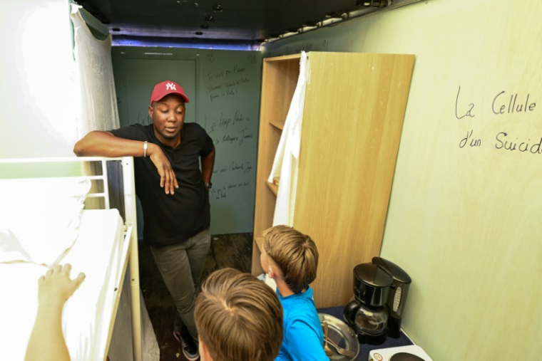 L'ex-détenu Adama Camara s'entretient avec des écoliers lors de la visite de sa "Grotte Mobile", un camion où il a reconstitué son ancienne cellule pour "sensibiliser" les jeunes à la vie en prison, le 11 juin 2025 à Drancy, en Seine-Saint-Denis ( AFP / Hugo MATHY )