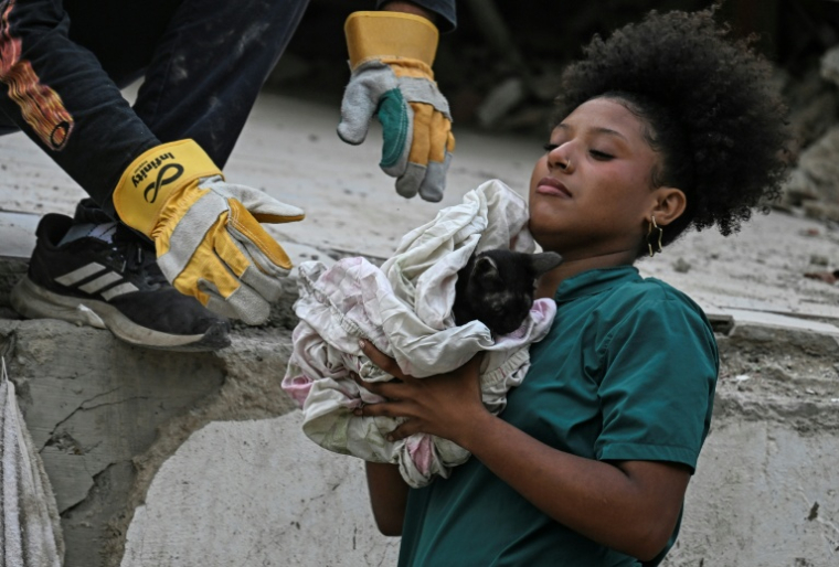 Une secouriste bénévole porte un chat sorti des décombres d'un immeuble détruit par les séismes du 24 juin à Caraballeda, au Venezuela, le 18 juillet 2026 ( AFP / Juan BARRETO )
