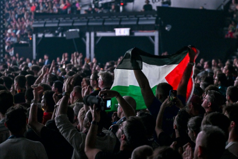 Un activiste pro-palestinien brandit un drapeau palestinien pendant que la chanteuse israéliennne Yuval Raphael se produit lors de la répétition générale de l'Eurovision, à Bâle, le 16 mai 2025 ( AFP / Fabrice COFFRINI )