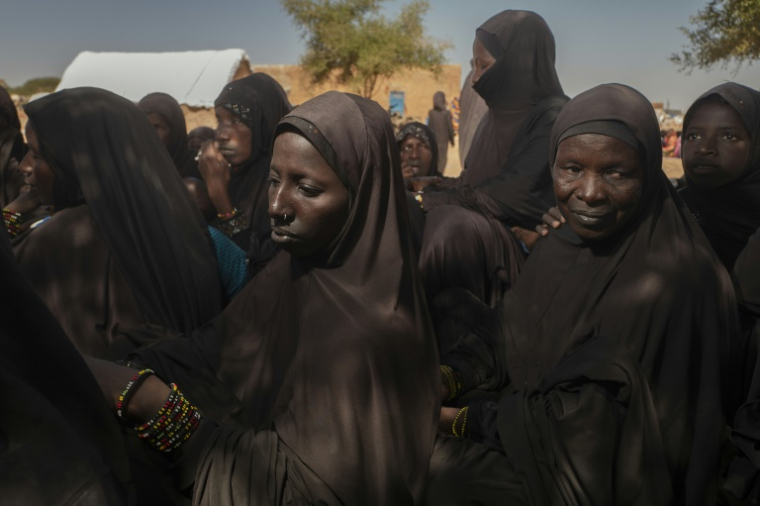 Des femmes réfugiées peules portant le voile imposé par le Groupe de soutien à l'islam et aux musulmans (JNIM), une branche d'Al-Qaïda au Mali, font la queue dans le village de Mekhal Oualad Zeid, à quelques kilomètres de la frontière entre la Mauritanie et le Mali, à Fassale, le 5 novembre 2025. ( AFP / MICHELE CATTANI )