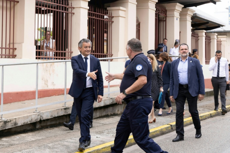 Le ministre de la Justice Gerald Darmanin (g) salue un officier de police dans les rues de Cayenne lors de sa visite en Guyane, le 19 mai 2025 ( AFP / Ronan LIETAR )