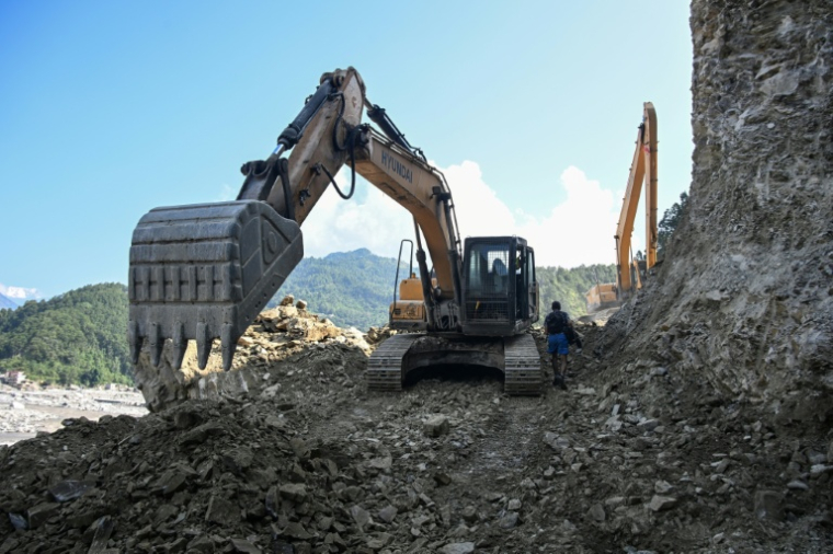Des ouvriers dégagent une route avec des pelleteuses le long de la rivière Trishuli dans le district de Nuwakot, au Népal, le 1er octobre 2026 ( AFP / Prakash MATHEMA )