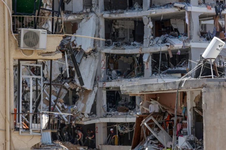Des secouristes israéliens fouillent les décombres d'un bâtiment touché par des tirs de missiles iraniens dans la ville côtière de Bat Yam, au sud de Tel-Aviv, le 15 juin 2025 ( AFP / GIL COHEN-MAGEN )
