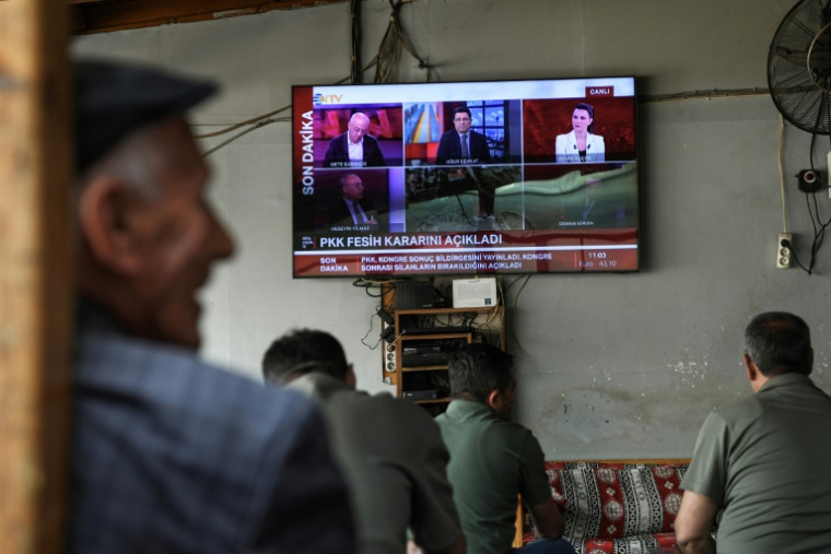 Des hommes regardent l'annonce de la dissolution du PKK sur un écran de TV à Diyarbakir, en Turquie, le 12 mai 2025 ( AFP / Ilyas AKENGIN )