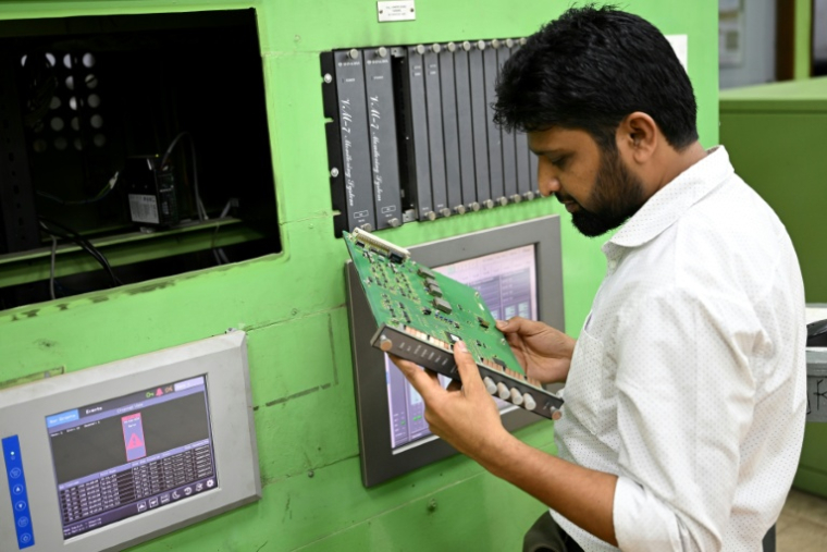 Un employé inspecte une plaque de circuits dans la salle de contrôle de l'usine d'engrais de Ashuganj, à l'arrêt depuis un an, le 12 août 2026 à Brahmanbaria, dans l'est du Bangladesh ( AFP / Salahuddin Ahmed )