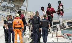Des migrants débarquent du navire l'Argonaute ; ils ont été secourus en mer après que leur embarcation a pris feu lors d'une tentative de traversée de la Manche au port de commerce de Boulogne-sur-Mer, le 4 août 2026 ( AFP / Sameer AL-DOUMY )