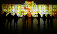 Des passants devant le palais Saint-Pierre illuminé avec "Le Lundi c’est Raviolis" de l'artiste Tigrelab durant l'avant première de la Fête des lumières à Lyon, le 4 décembre 2025 ( AFP / Alex MARTIN )