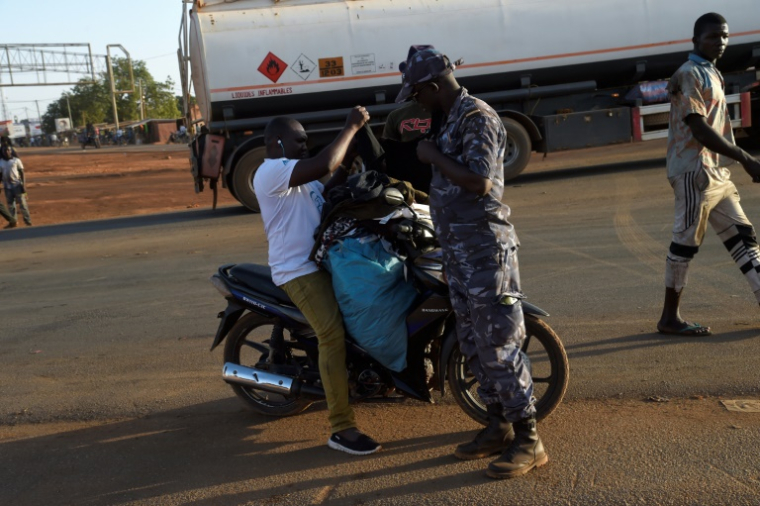 Un policier fouille un vendeur à moto à Cinkassé, un poste frontalier commercial du nord du Togo avec le Burkina Faso, le 16 février 2020 ( AFP / PIUS UTOMI EKPEI )