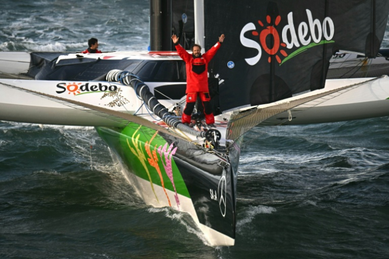 Thomas Coville célèbre son record du tour du monde à la voile (Trophée Jules Verne) dimanche matin quelques instants après avoir passé la ligne d'arrivée au large de Brest avec son équipage sur Sodebo Ultim. ( AFP / LOIC VENANCE )