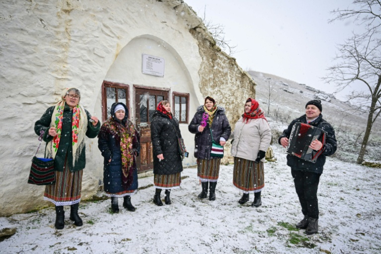 Des femmes du village de Rogojeni, en costumes traditionnels moldaves, chantent des chants de Noël près d'une maison-musée "basca", le 4 janvier 2026 ( AFP / Daniel MIHAILESCU )