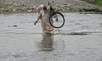 Un homme traverse une rue inondée de Karachi, mégapole du Pakistan où les pluies de mousson ont fait plus de 400 morts en une semaine, le 20 août 2025 ( AFP / Rizwan TABASSUM )