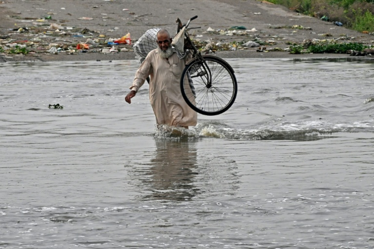 Un homme traverse une rue inondée de Karachi, mégapole du Pakistan où les pluies de mousson ont fait plus de 400 morts en une semaine, le 20 août 2025 ( AFP / Rizwan TABASSUM )