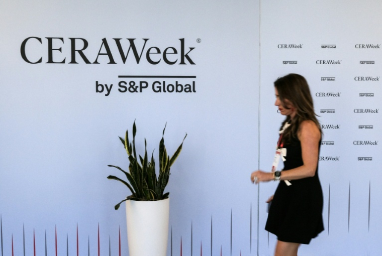 Une femme passe devant un panneau de la CERAWeek, plus grand rassemblement annuel des acteurs du pétrole, le 22 mars 2026 à Houston, au Texas ( AFP / RONALDO SCHEMIDT )