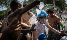 Un groupe d'adolescents asperge d'eau un jeune homme circulant en scooter près du canal Saint-Martin, à Paris, le 24 juin 2026 ( AFP / Simon WOHLFAHRT )