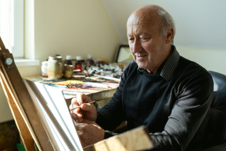 Le peintre d'art naïf Pavel Hajko travaille dans son atelier à Kovačica, dans le nord de la Serbie, le 16 octobre 2025 ( AFP / Andrej ISAKOVIC )