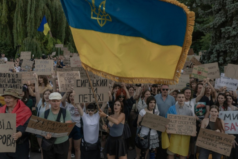 Des manifestants brandissent un drapeau ukrainien lors d’une manifestation contre la décision du président ukrainien de limoger le ministre de la Défense Mykhaïlo Fedorov, à Kiev le 18 juillet 2026 ( AFP / Roman PILIPEY )
