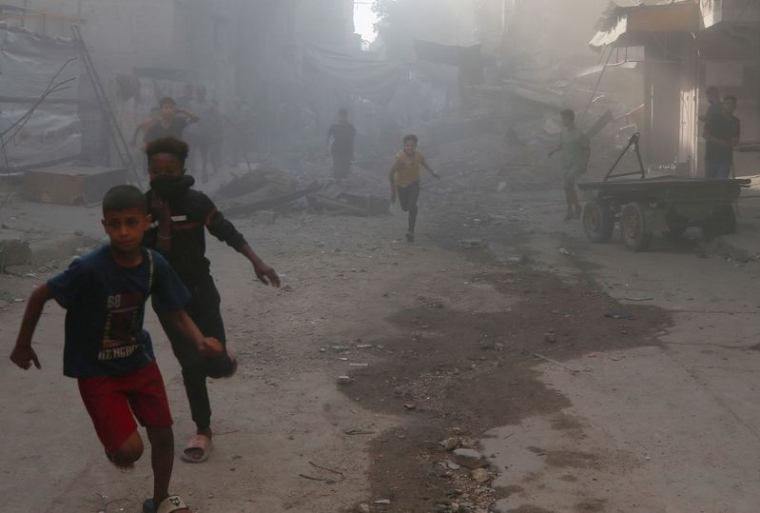 Palestinians inspect the site of an Israeli air strike on a house in Gaza City