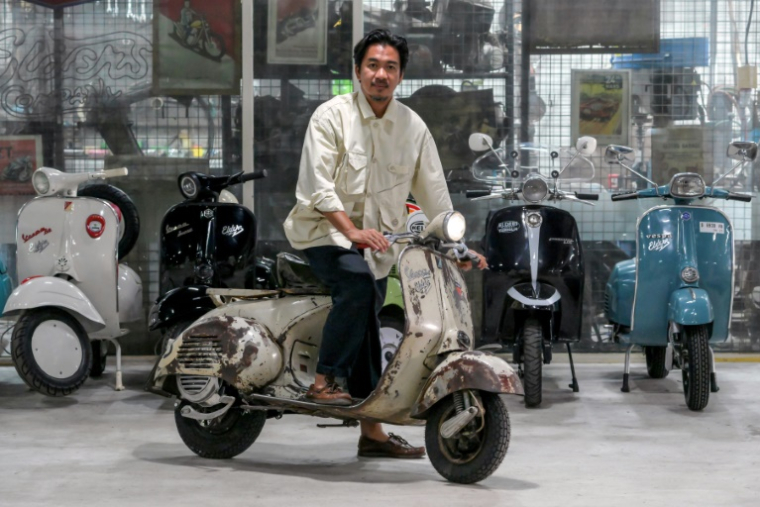 Heret Frasthio, patron de l'atelier Elders, pose sur une Vespa convertie à l'électrique, le 3 mars 2025 à Jakarta ( AFP / BAY ISMOYO )
