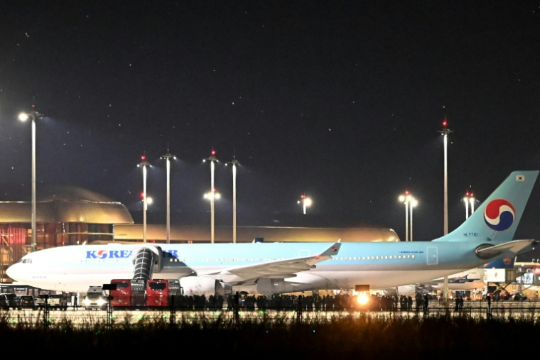 Des policiers cambodgiens et sud-coréens près de l'avion affrété pour rapatrier la soixantaine de Sud-Coréens soupçonnés d'implication dans des arnaques en ligne au Cambodge, à l'aéroport international de Techo, le 18 octobre 2025 ( AFP / TANG CHHIN Sothy )