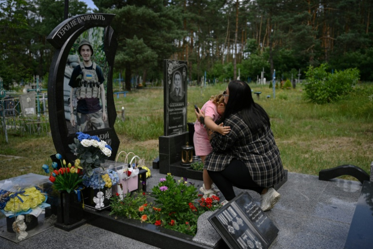 Lioudmyla (à droite), 27 ans, veuve du soldat ukrainien Andriï Doubnytsky, et sa fille Mia (à gauche), 4 ans, visitent sa tombe dans un cimetière du village de Stepantsi, dans la région de Tcherkassy, le 7 juillet 2026. ( AFP / Genya SAVILOV )