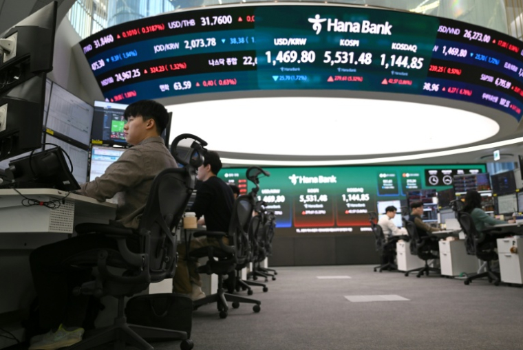 Des cambistes surveillent les taux de change tandis qu'un écran électronique affiche les indices boursiers de référence dans une salle des marchés des changes de la Hana Bank à Séoul, le 10 mars 2026 en Corée du Sud ( AFP / Jung Yeon-je )