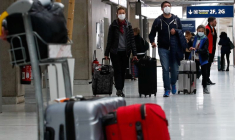 Des personnes portant des masques de protection arrivent à l'aéroport Charles de Gaulle près de Paris