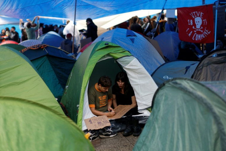 Des manifestants préparent des pancartes sous une tente, dans un campement installé pour protester contre les expulsions et la crise du logement devant le siège de la présidence de la Communauté de Madrid, Puerta del Sol, le 28 septembre 2026 ( AFP / Oscar DEL POZO )