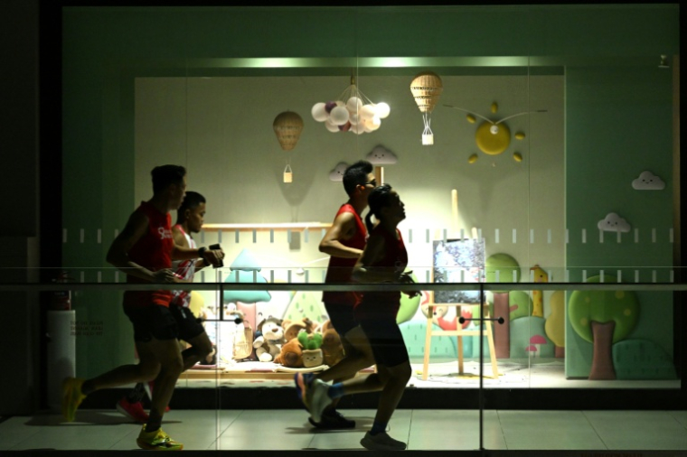 FDes joggeurs courent à l’intérieur d’un centre commercial en raison du brouillard de pollution extérieur, le 24 octobre 2026 à Singapour ( AFP / Roslan RAHMAN )