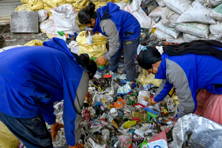 Des personnes trient les déchets récupérés sur les pentes de l'Everest pour les recycler à Katmandou, le 12 juin 2024 au Népal ( AFP / Prakash MATHEMA )