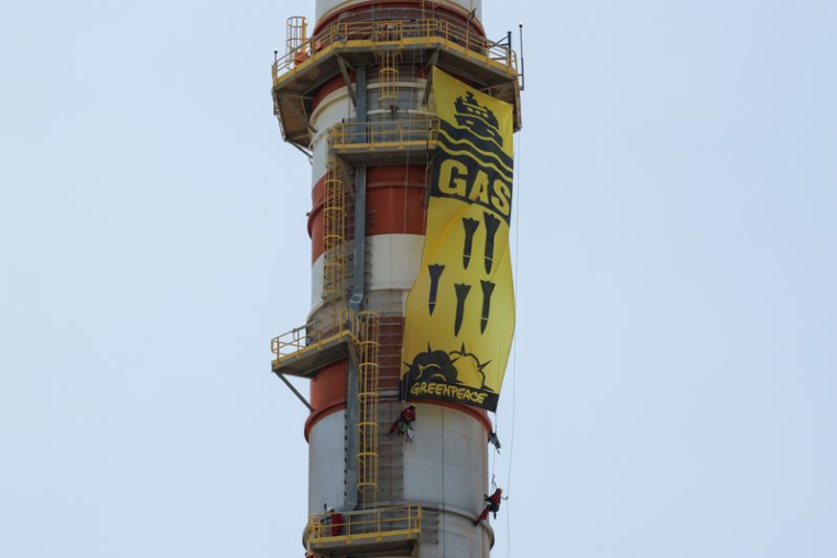 Des militants de Greenpeace affichent une bannière suspendue à une cheminée lors d'une manifestation contre l'entreprise énergétique Naturgy, à Campanillas