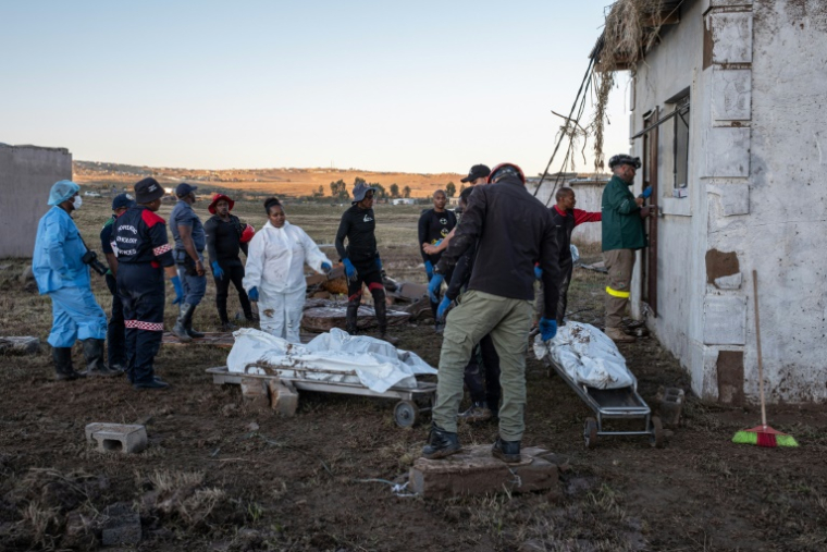 Des membres des services médicaux d'urgence (EMS) sortent des corps d'une maison après des inondations hivernales, le 12 juin 2025 près de Mthatha, en Afrique du Sud ( AFP / EMMANUEL CROSET )
