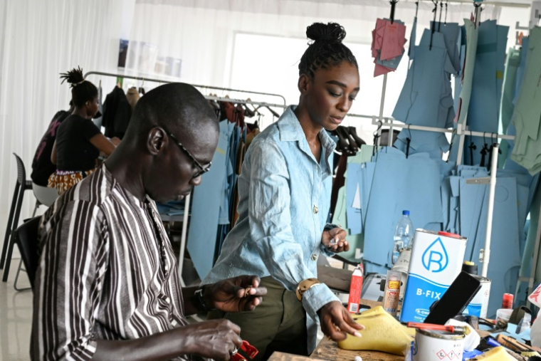 La styliste Loza Maléombho et l'un de ses employés dans son atelier du quartier populaire de Treichville, à Abidjan, le 26 juin 2026 en Côte d'Ivoire  ( AFP / Issouf SANOGO )