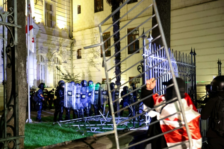Des manifestants face à la police anti-émeute alors qu'ils tentent de pénétrer dans l'enceinte du palais présidentiel lors d'un rassemblement de l'opposition le jour des élections locales, le 4 octobre 2025 à Tbilissi, en Géorgie ( AFP / Giorgi ARJEVANIDZE )