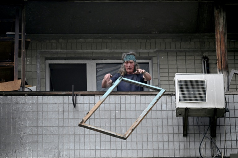 Un habitant jette des débris par le balcon de son appartement dans un immeuble résidentiel endommagé par une frappe de drone russe sur Kiev, le 24 mai 2025 en Ukraine ( AFP / Sergei SUPINSKY )